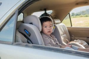 Little boy in a child safety seat sitting patiently in the back of a car.
