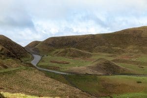 The road on the hills covered in greenery under the sunlight in the UK