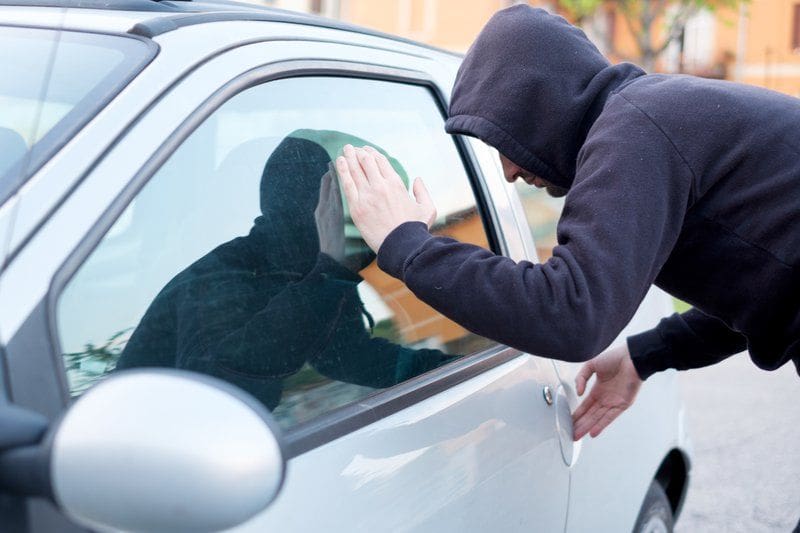 Thief looking inside a car window ready to steal something